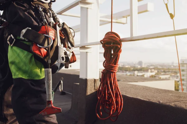 Equipment of industrial mountaineering worker on roof of building during industrial high-rise work. Climbing equipments before starting job. Rope laborer access. Concept of urban works. Copy space