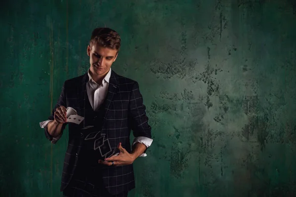 ギャンブルカードを持つ若い男のクローズアップ肖像画 ハンサムな男はトランプでトリックを示しています 緑のテクスチャの背景に魔術師の巧妙な手 エンターテインメントと趣味の概念 サイトのコピースペース — ストック写真