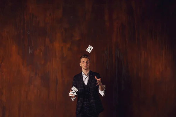 ギャンブルカードを持つ若い男のクローズアップ肖像画 ハンサムな男がカードを投げます 茶色のテクスチャの背景に魔術師の巧妙な手 エンターテインメントと趣味の概念 サイトのコピースペース — ストック写真