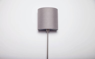 Beyaz duvara karşı abajurlu klasik Aydınlatılmış gri lamba. Abajur döşemeli geleneksel bir lamba. Yaratıcılık geçmişi. Yer veya pankart için alanı kopyala