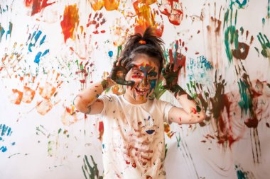 Suluboya ile oynayan mutlu genç bir çocuğun portresi. Rastgele boyanmış çocuk yüzü ve giysileri. Çocuk eğlencesi, sanat oyunları ve holiganlığı kavramsallaştır. Holi festivali için renkli görüntü. Boşluğu kopyala