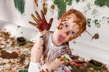 Suluboya ile oynayan mutlu genç bir çocuğun portresi. Çocuk yüzü ve kıyafetleri boyayla boyanmış. Çocuk eğlencesi, sanat oyunları ve holiganlığı kavramsallaştır. Holi festivali için renkli görüntü. Boşluğu kopyala