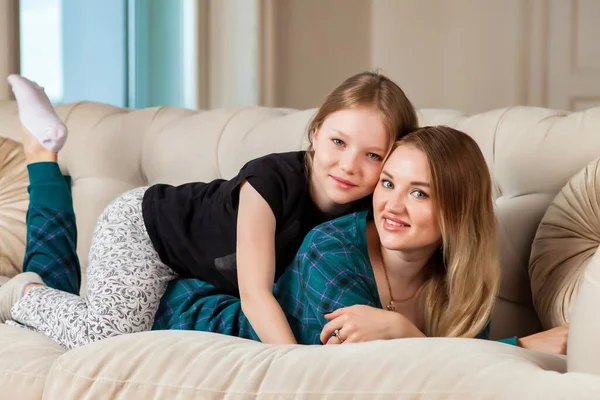 快乐漂亮的母亲和她可爱的女儿穿着休闲装躺在客厅的沙发上 与孩子和家人相处的概念很可爱 网站的复制空间 — 图库照片