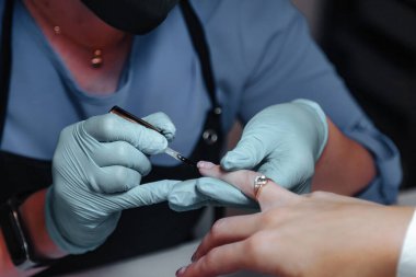 Manikür ustası kuaförde genç ve güzel bir kadın tırnaklıyor. Dahili salondaki müşteri hizmetleri inanılmaz bir imaj yaratıyor. İş yaratma büyücüsü. Ölçülü tatmin kavramı. Boşluğu kopyala