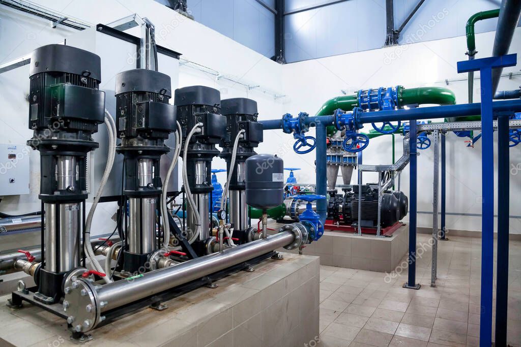 Industrial interior of water pump, valves, pressure gauges, motors inside engine room. Valve and pumps in an industrial room. Urban modern powerful pipelines and pumps, automatic control systems