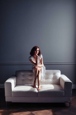 Woman middle aged relaxing on comfortable soft sofa in living room at cozy home or hotel, calm satisfied female relaxed on couch. Concept of comfort, privacy and relaxation. Copy space