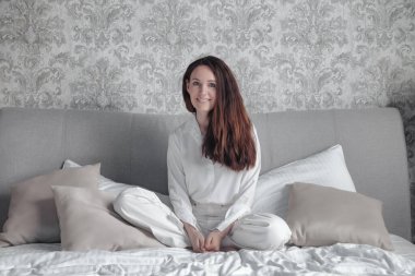Woman middle aged relaxing on comfortable soft bed in bedroom at cozy home or hotel, calm satisfied female relaxed on couch. Concept of comfort, privacy and relaxation. Copy space