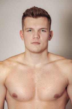 Işık yalıtılmış arka planda atletik yapılı yakışıklı genç bir adamın portresi. Yakışıklı, kaslı, kaslı bir adam. Spor anlayışı, beden eğitimi, fitness ve sağlıklı yaşam tarzı. Boşluğu kopyala