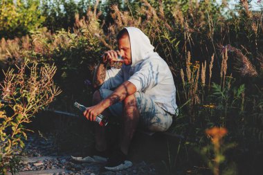 Genç adam gün batımında terk edilmiş bir demiryolunda alkol içiyor. Üzüntü, ilgisizlik, depresyon ya da yanlış yaşam tarzı kavramı. Boşluğu kopyala