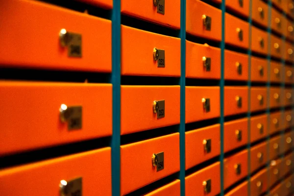 Orange Mailboxes in an apartment residential building. Even rows of numbered mailbox. Correspondence concept in city. You can use it as background for your creative. Copy space