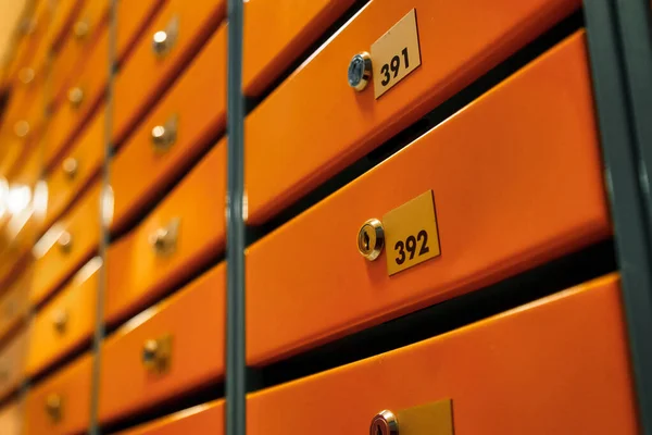 Orange Mailboxes in an apartment residential building. Even rows of numbered mailbox. Correspondence concept in city. You can use it as background for your creative. Copy space
