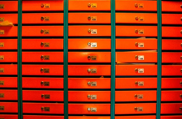 Orange Mailboxes in an apartment residential building. Even rows of numbered mailbox. Correspondence concept in city. You can use it as background for your creative. Copy space