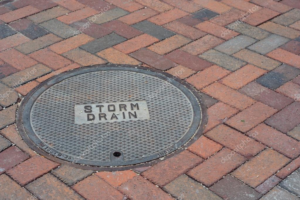 Storm Drain Cover on a Brick Road Stock by ©-Strider- 77487262