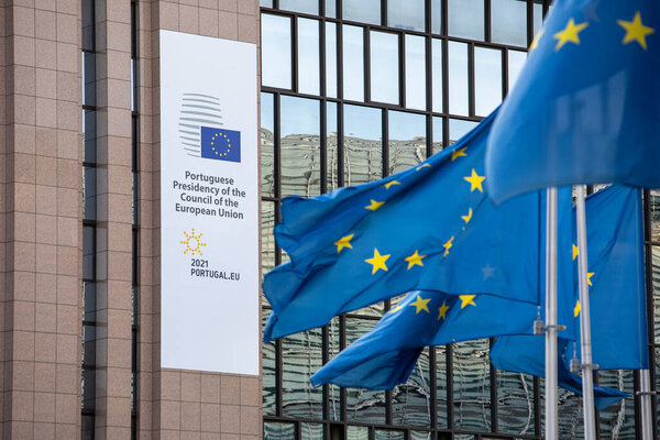 Брюссель, Бельгия - 22 января 2021 года: Европейские флаги развеваются на ветру перед Европейским Советом с логотипом португальского председательства