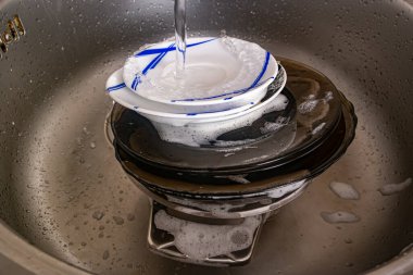 Lavaboda bir yığın kirli sabunlu bulaşık var.