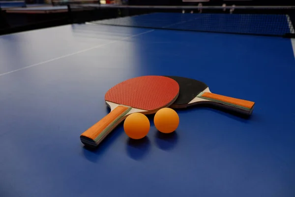 on the tennis table is a ball and two table tennis rackets