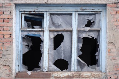 Kırık camlı tuğla bir evin penceresi.