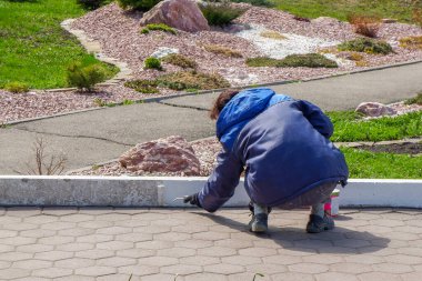 Bir çalışan kaldırımı beyaz boyayla boyuyor. Şehir hizmetleri, yakın plan.