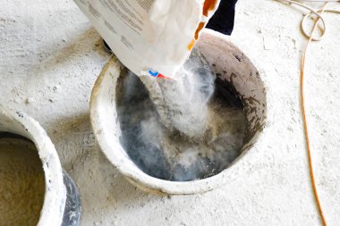 İnşaatçı, havan topuna yol göstermesi için yapı karışımını bir konteynıra boşaltır.,