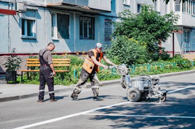 Bir yol işçisi, konut binasının avlusundaki bir otoparka işaret koyuyor...