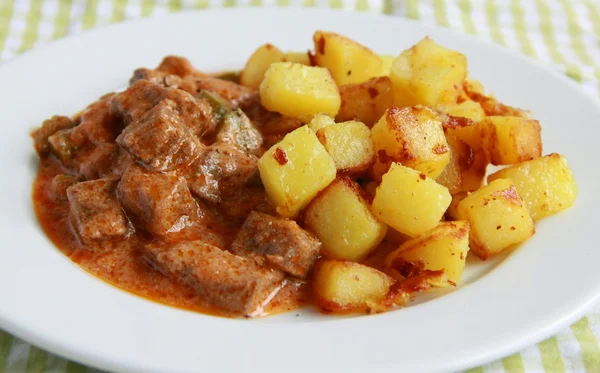 Beef in tomato sauce with potato fries.