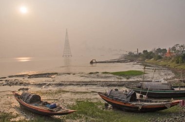 Diamond Harbor 'da kış öğleden sonrası fotoğrafı. Ufuktan ayrılan güneş, altından parıltısıyla Ganj kıyılarında batıyor. Nehir boyunca bir sis tabakası oluşuyor..