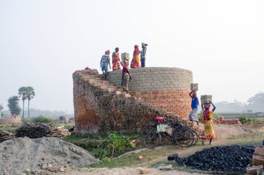 Hooghly bölgesinde 12 Aralık 2020 'de Hooghly West Bengal Hindistan' da bir tuğla fırının resmi. Yetişkin erkek ve kadın işçiler fırındaki çiğ tuğlaları pişirmek için çok çalışıyorlar..