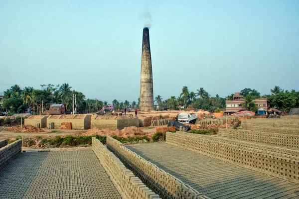 13 Aralık 2020 Elmas Limanı Batı Bengal Hindistan: Kırsal Bengal 'de tuğla fırınlarının resimleri. Tuğla ocağı boyunca bir yığın çiğ tuğla ve bitmiş tuğlalar. Tuğla fırınının bacasından fışkırıyor..