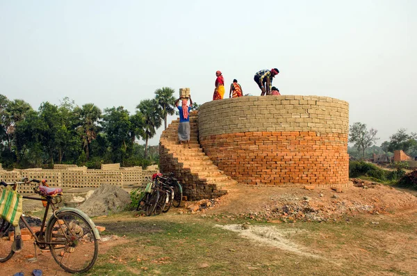 Hooghly bölgesinde 12 Aralık 2020 'de Hooghly West Bengal Hindistan' da bir tuğla fırının resmi. Yetişkin erkek ve kadın işçiler fırındaki çiğ tuğlaları pişirmek için çok çalışıyorlar..