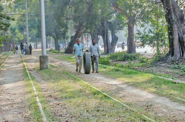 kolkata west bengal india on 27th december 2020:Two people are taking a punctured tire of a bus on a winter afternoon in Kolkata Maidan area.