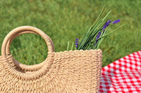 Bolsa de paja con flores de campo en el prado. Concepto de picnic de verano —  Fotos de Stock