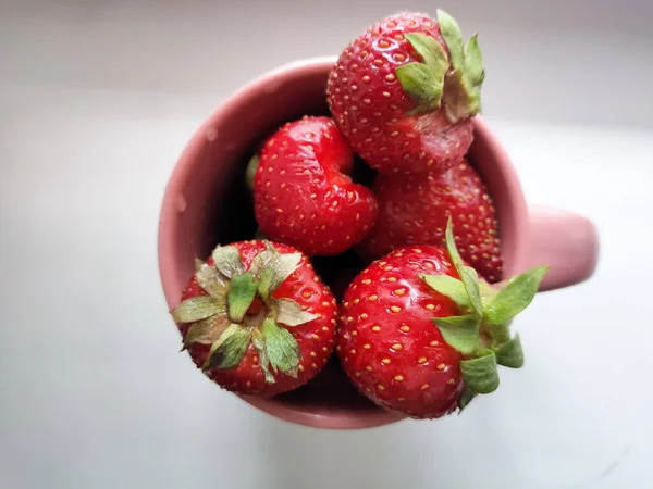 Frische rote Erdbeere in rosa Tasse auf weißem Hintergrund — Stockfoto