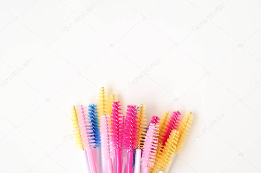 colored brushes for lash extensions in beauty salon,materials for lashmaker on white background, copy space