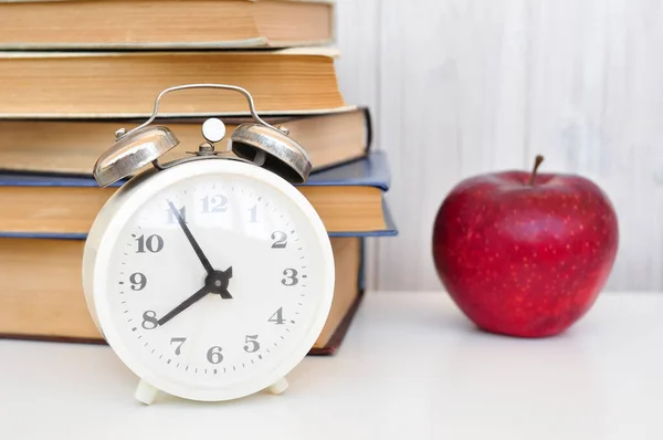 alarm clock, red apple  and books work and study morning concept