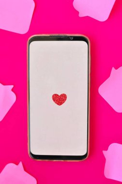Kırmızı arka planda kırmızı kalp etiketi olan akıllı telefon aygıtı 