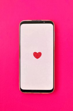 Kırmızı arka planda kırmızı kalp etiketi olan akıllı telefon aygıtı 