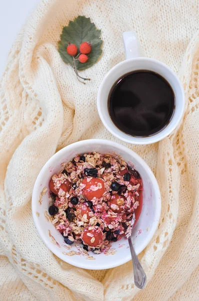 Un plato de avena con bayas y una taza de café — Foto de Stock