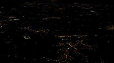 Aerial night view from airplane window showing glowing city lights below