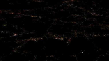 Aerial night view from airplane window showing glowing city lights below