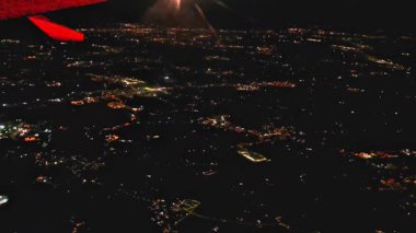 Aerial night view from airplane window showing glowing city lights below