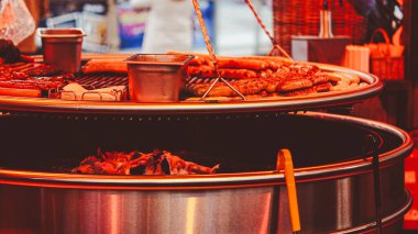 Yanan Noel tezgahlarıyla çevrili ızgarada pişen sıcak sosisler.