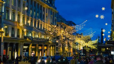 Regent Caddesi, kışın 7.11.2025 Londra, İngiltere 'de altın Noel çelenkleriyle parıldıyor.