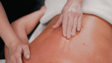 Sarışın müşterinin spa 'da rahatlamasını destekleyen nazik masaj hareketleri.