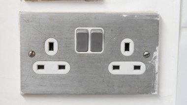 Elektrik prizinde çift anahtarlar ve desenli bir duvarda çoklu prizler var