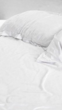 Yumuşak beyaz yatak ve iki yastık. Parlak, minimalist bir odada bir yatağa dizilmiş.