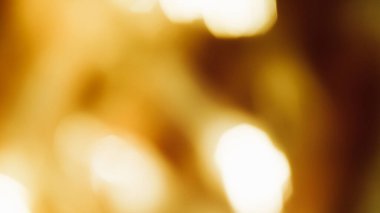 Sıcak altın bokeh ışıkları yumuşak odak efektiyle soyut bulanık bir arkaplan oluşturur