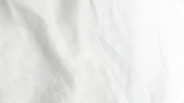 Beyaz kumaşın, doğal ışıkta yumuşak kıvrımlar ve kırışıklıklar gösteren detaylı görünümü