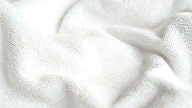 Yumuşak kıvrımları ve doğal ışık kırışıklıklarını gösteren desenli yüzeyi olan beyaz kumaş.