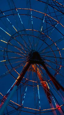 Dönme dolap yapısı gece gökyüzünde parlayan parlak ışıklarla çarpıcı bir manzara yaratıyor.