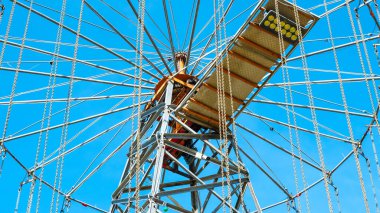 Dönme dolabın iskeletinin yakın görüntüsü ve parlak mavi gökyüzüne karşı destek kabloları